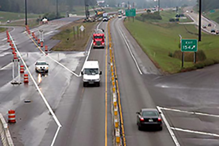 [Image Description]Cars and trucks driving through a construction site on a highway.